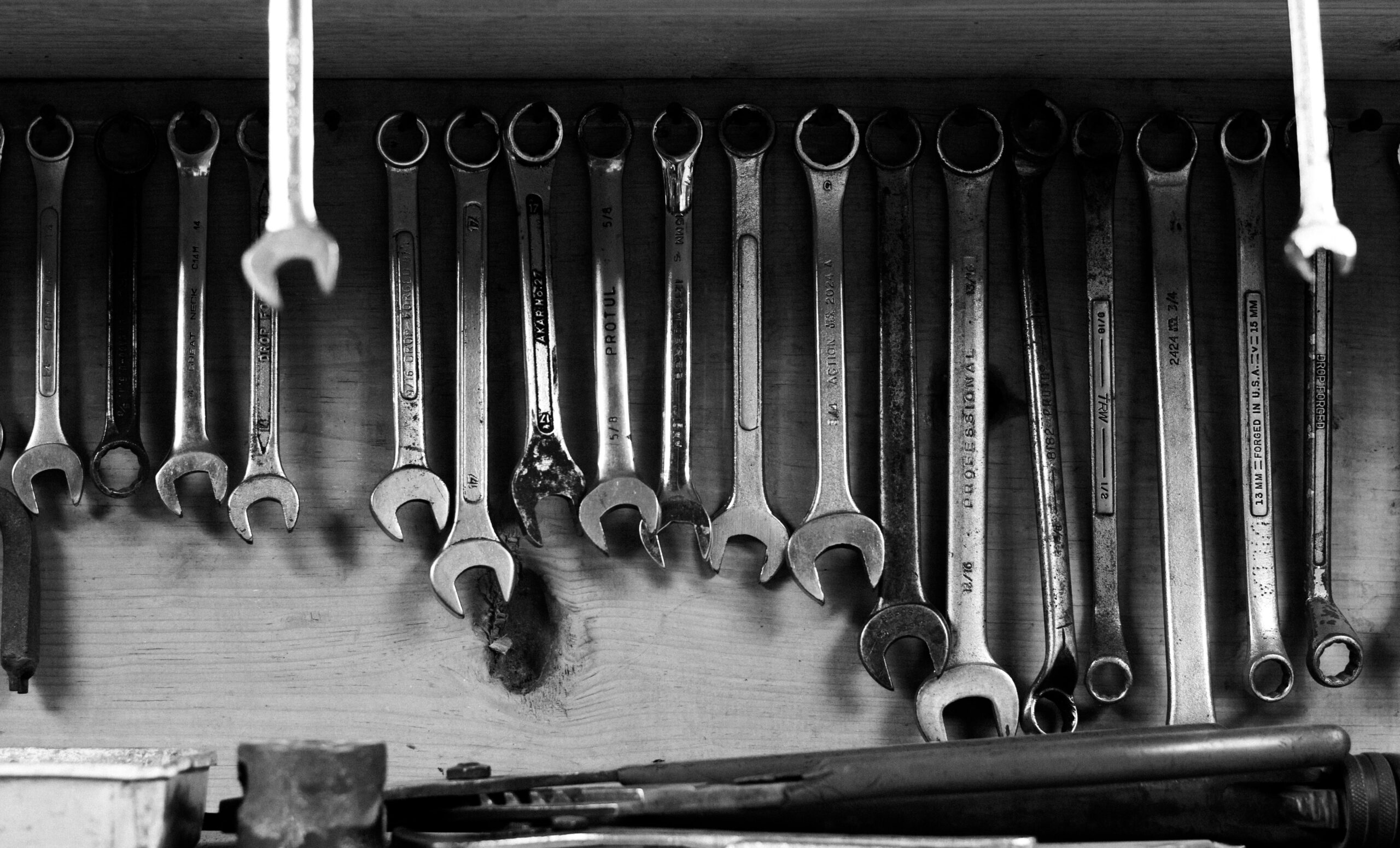 A black and white image of wrenches neatly hanging on a workshop wall.