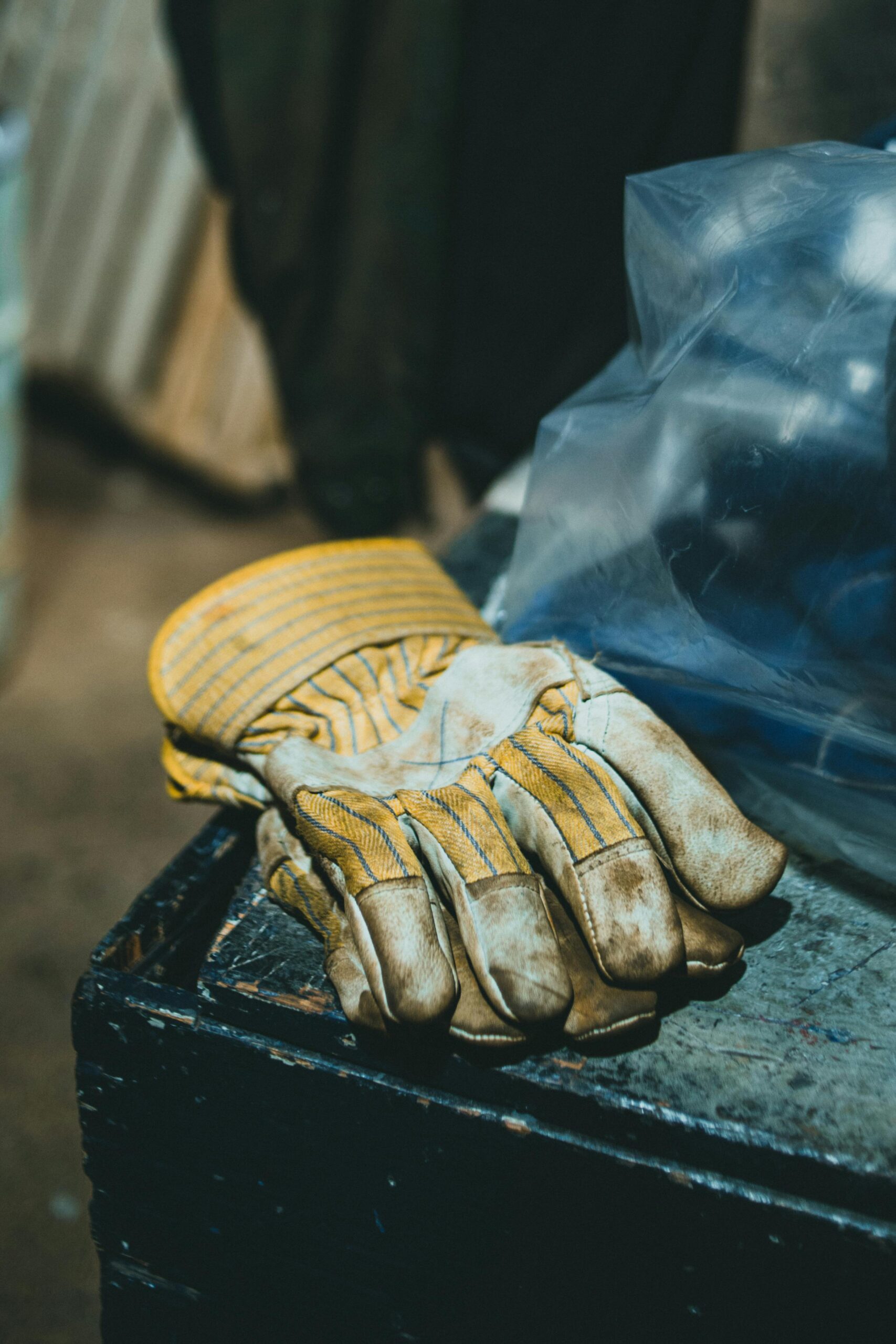 Close-up of worn work gloves on a gritty industrial surface, highlighting labor and craftsmanship.